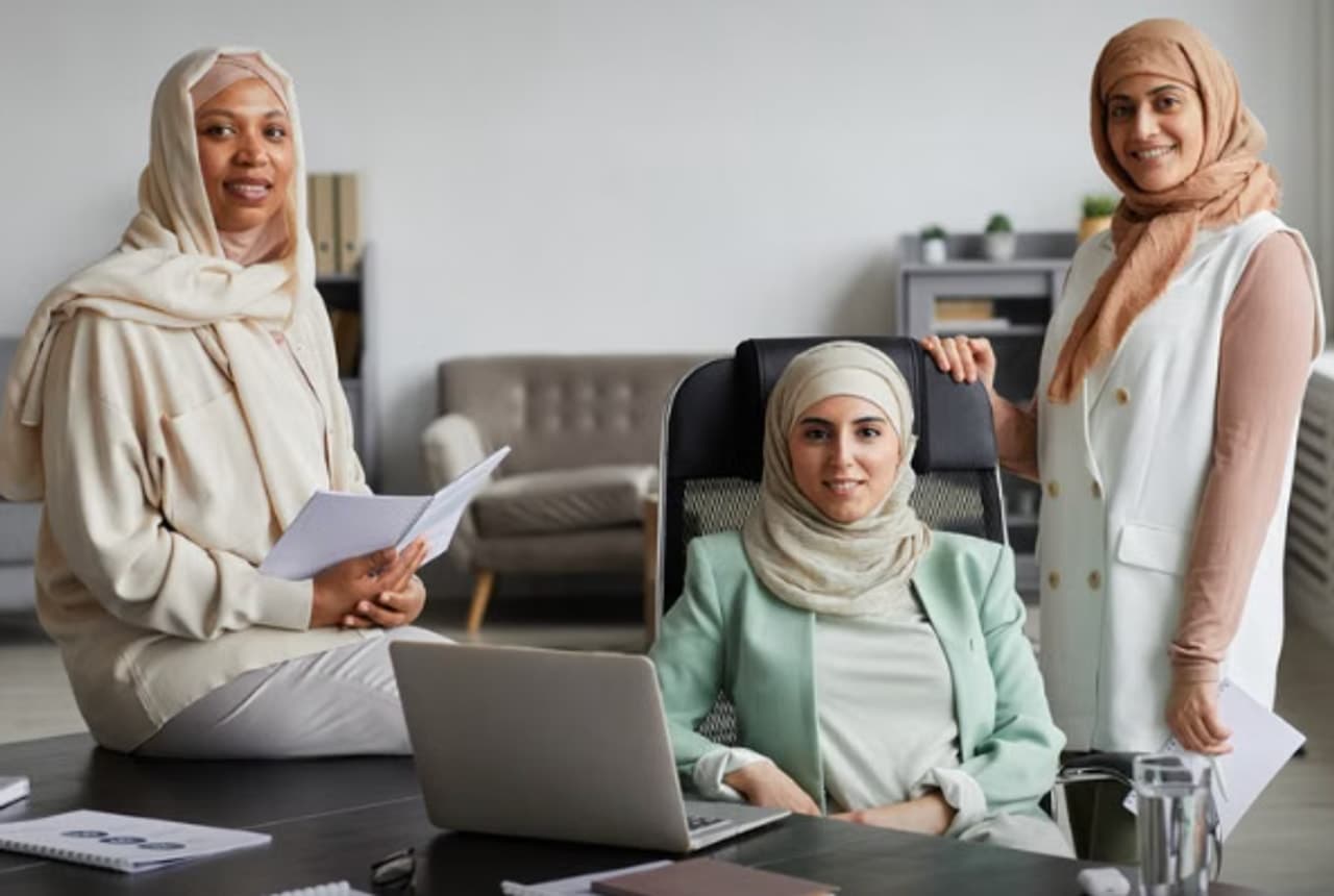Three professional women collaborating around a conference table with notes and a laptop.